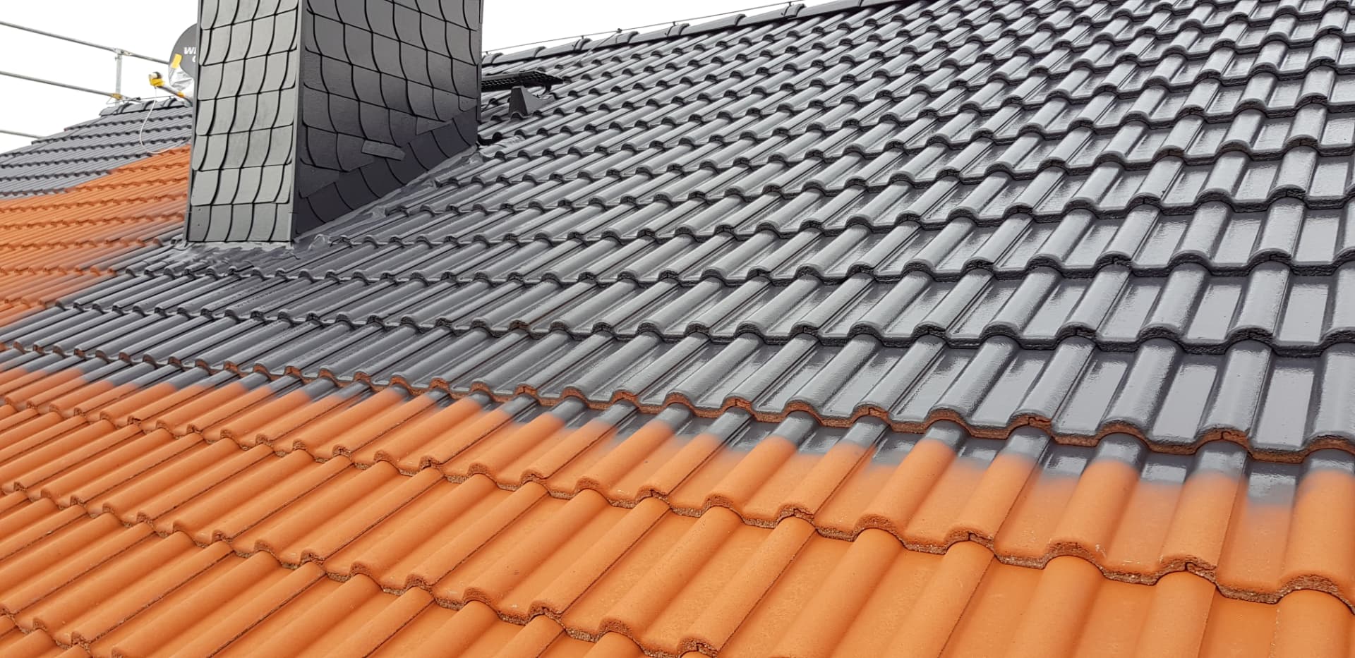 Dachbeschichtung in Arbeit: rote Betondachsteine werden anthrazit beschichtet